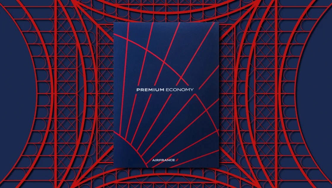 Menu Premium Economy Air France bleu marine posé sur un motif architectural rouge