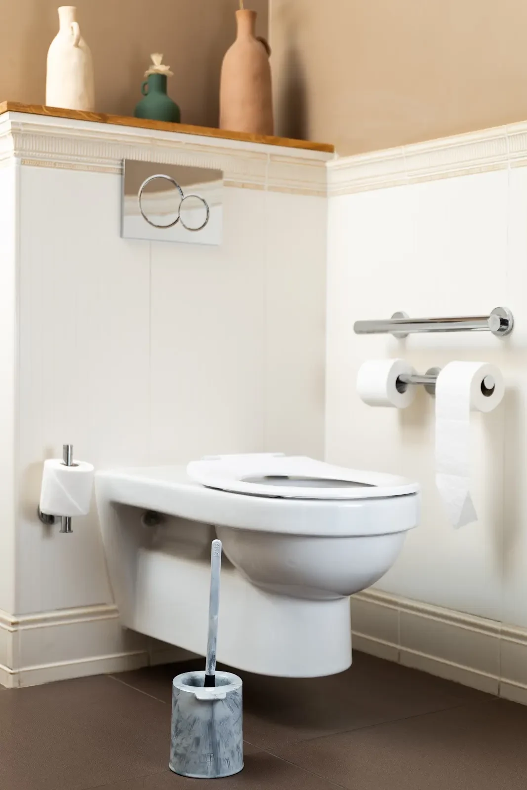 Salle de bains claire avec bbb La Brosse et son support placés devant des toilettes suspendues