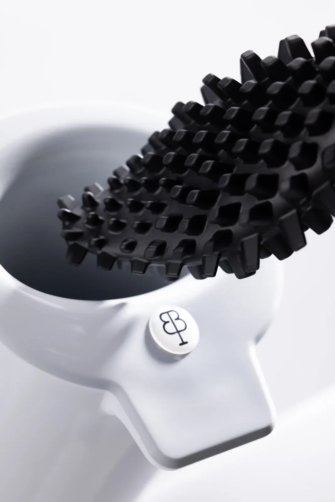 Gros plan sur les reliefs noirs de bbb La Brosse au-dessus de son support blanc marqué du monogramme BIOM