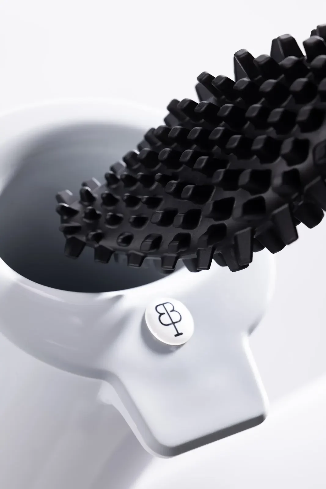 Gros plan sur les reliefs noirs de bbb La Brosse au-dessus de son support blanc marqué du monogramme BIOM