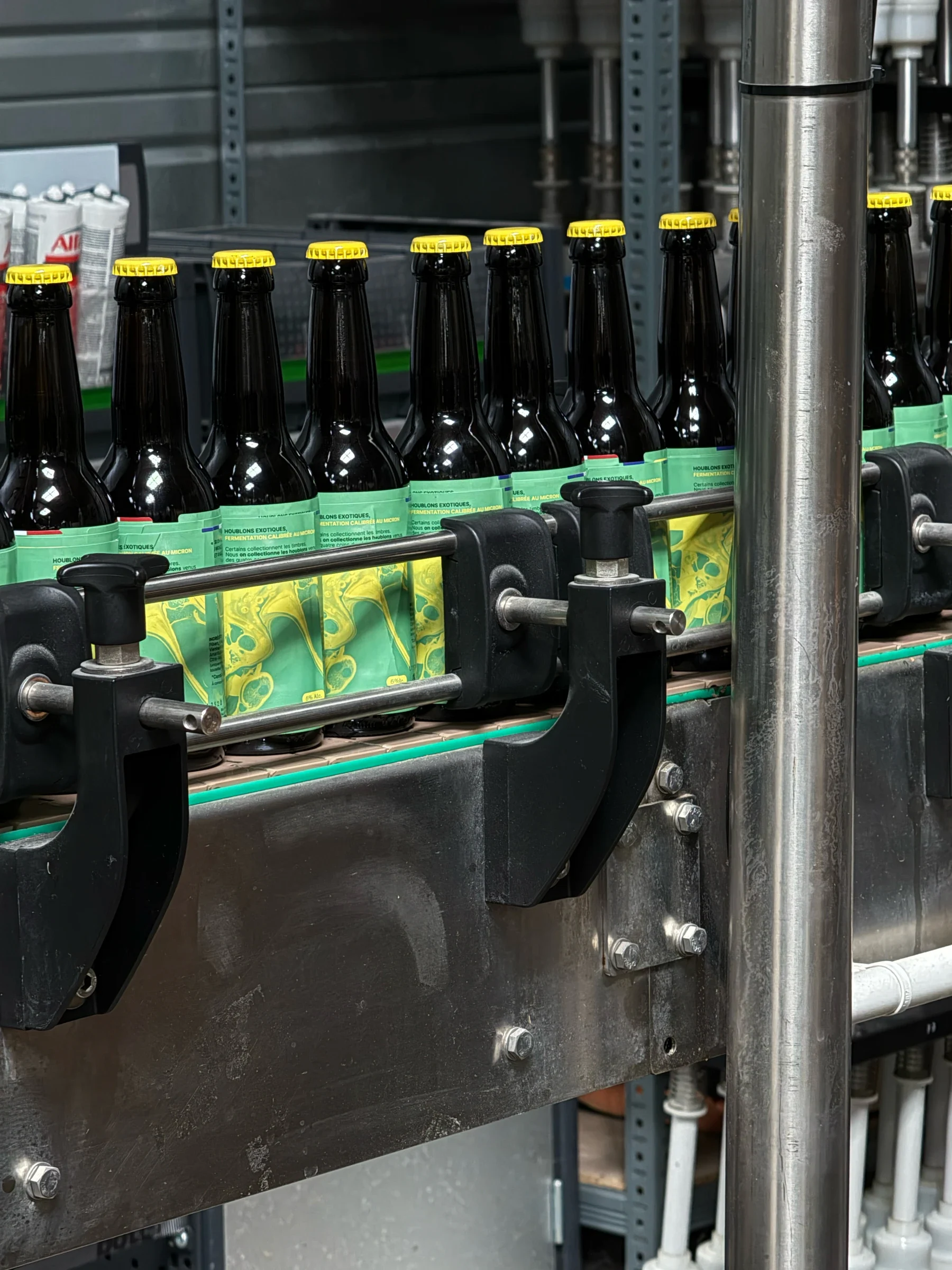 Bouteilles Hop Lab sur une chaîne d’embouteillage, avec étiquettes Pi vertes et jaunes imprimées et capsules jaunes