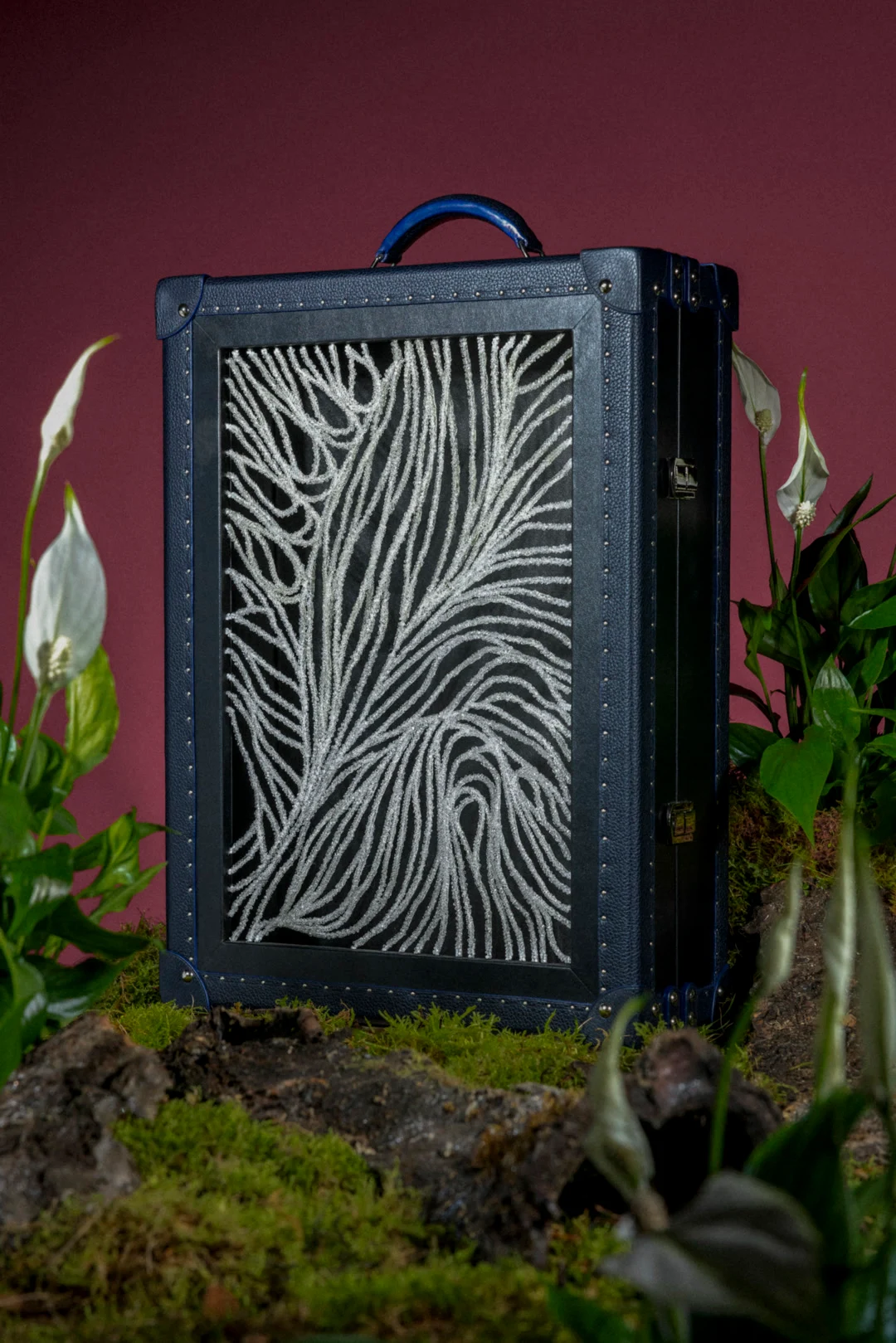 Malle verticale ornée d’un motif textile photographiée dans un décor végétal