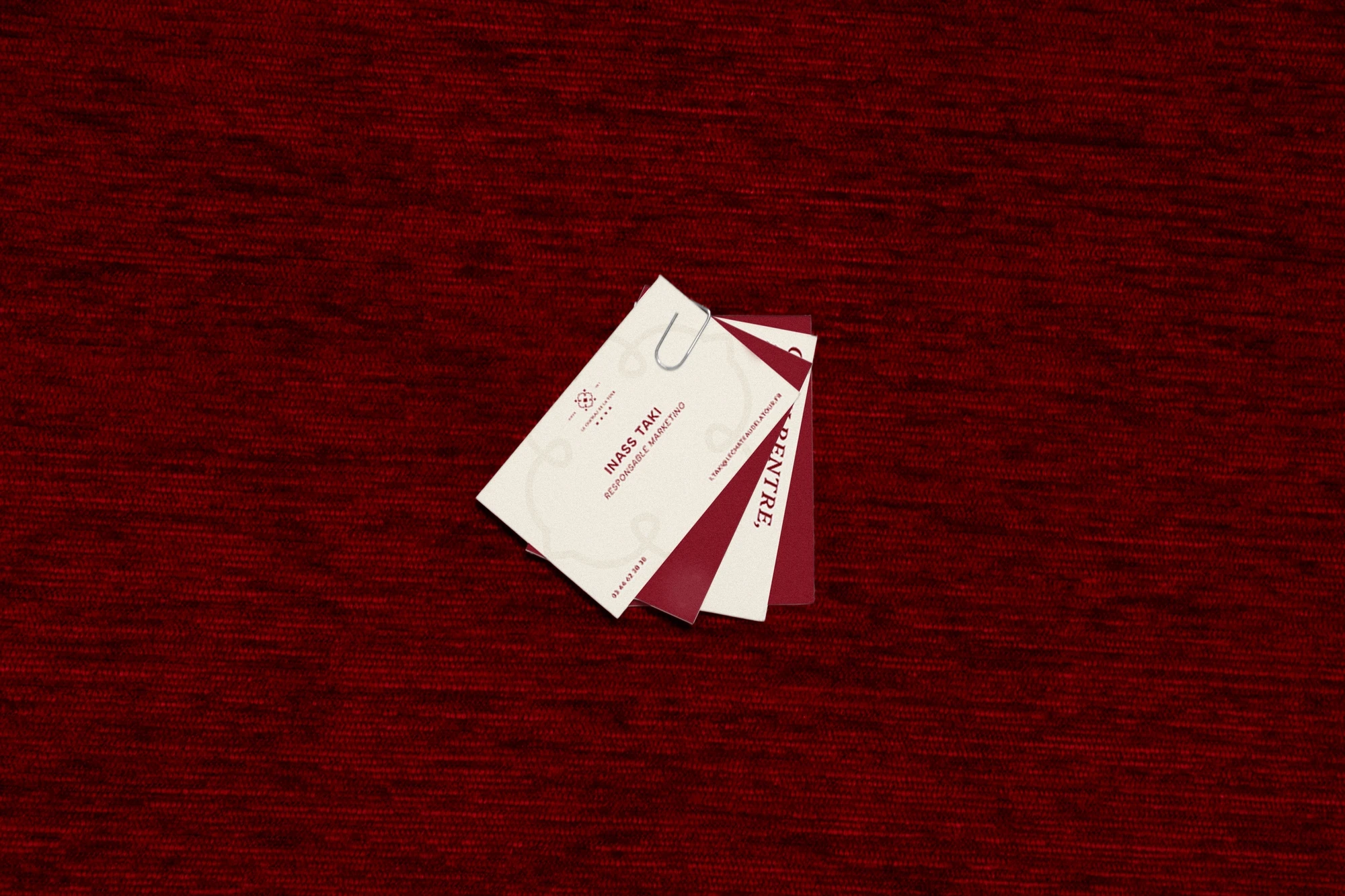 Cartes de visite ivoire et bordeaux du Château de la Tour posées sur un textile rouge profond