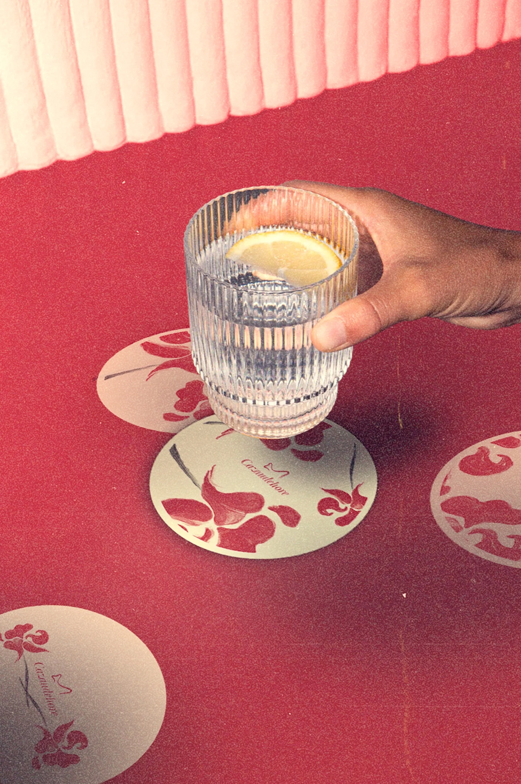Sous-bocks Cazaudehore photographiés sur une table rouge avec un verre