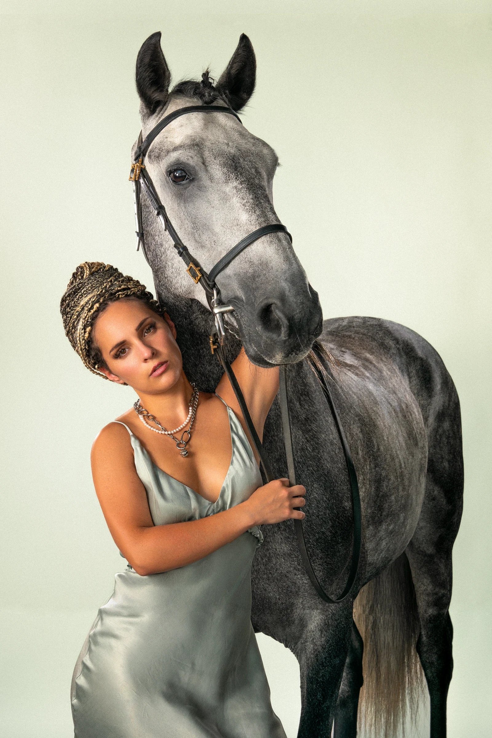 Portrait livré Soft Horse, modèle en robe satinée appuyée contre l’encolure d’un cheval gris