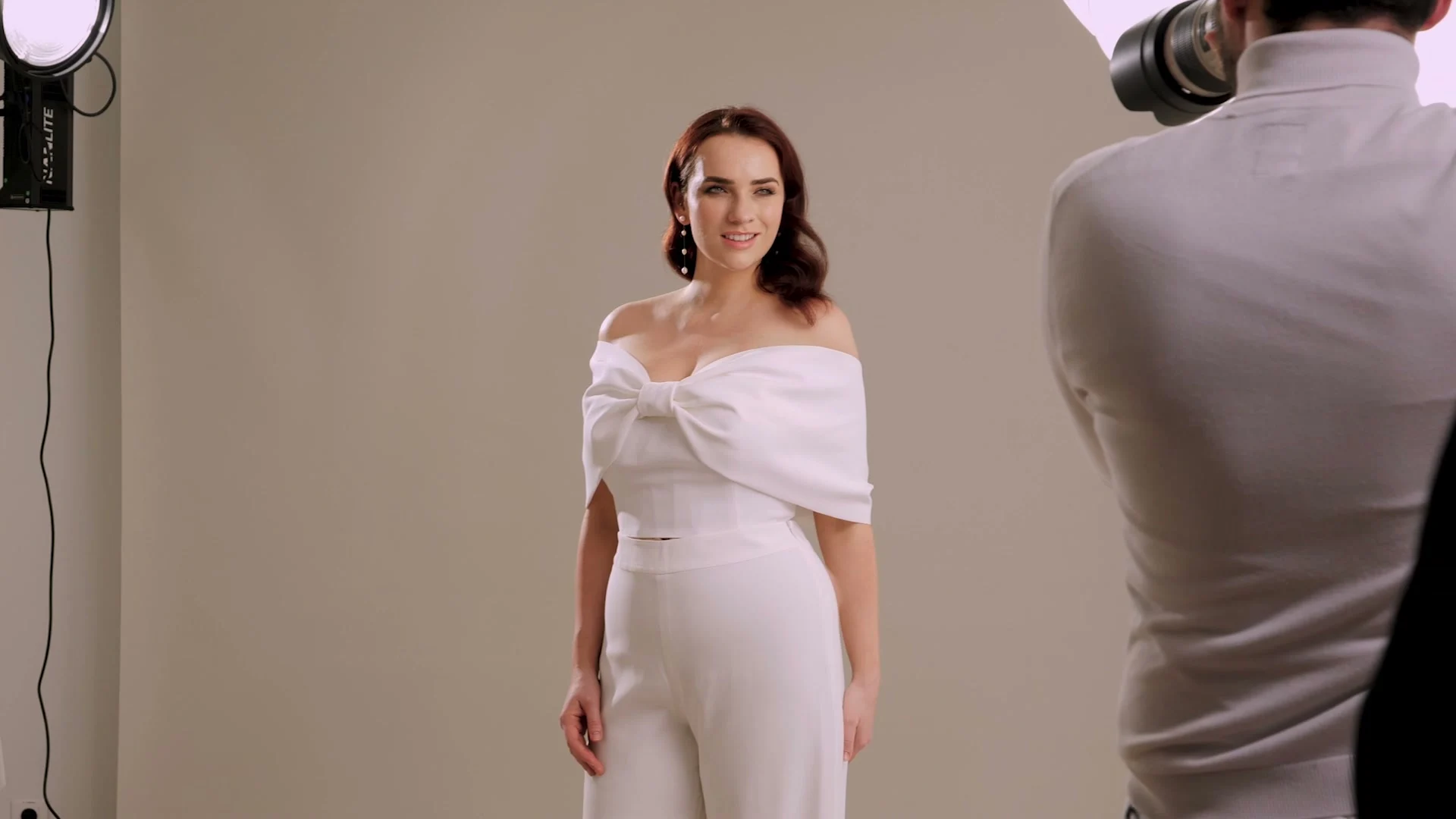 Coulisses du tournage Back to Glam, modèle en tenue blanche face à la caméra et aux éclairages