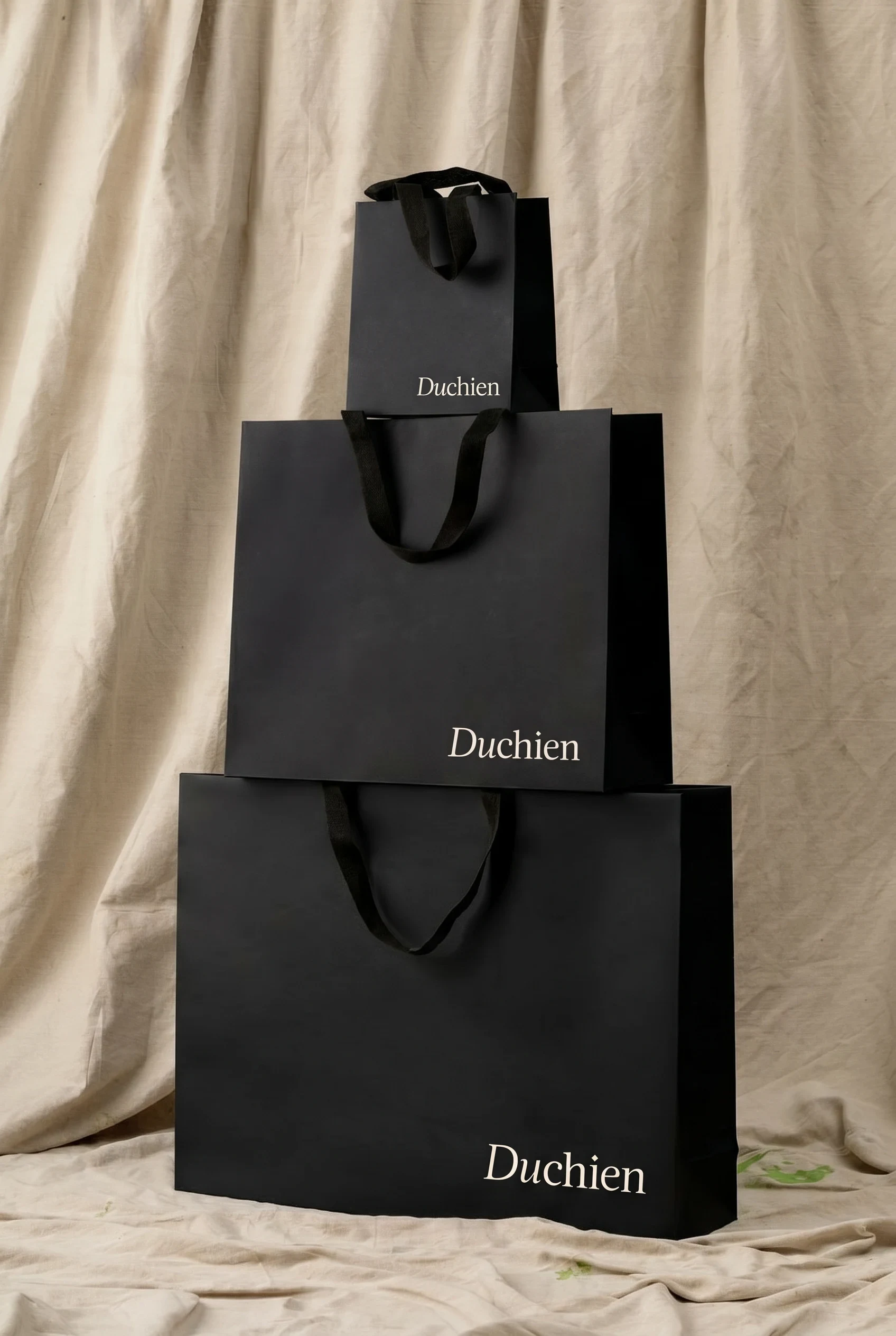 Trois sacs noirs Duchien composés devant un fond de toile naturelle