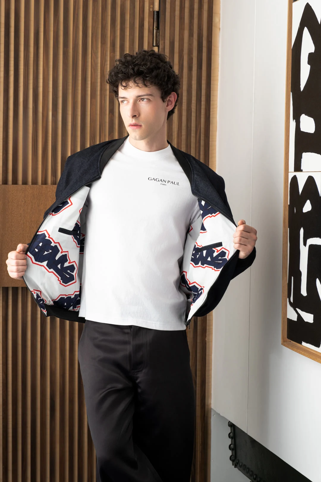 Modèle portant un tee-shirt blanc et une veste noire Gagan Paul ouverte sur une doublure illustrée