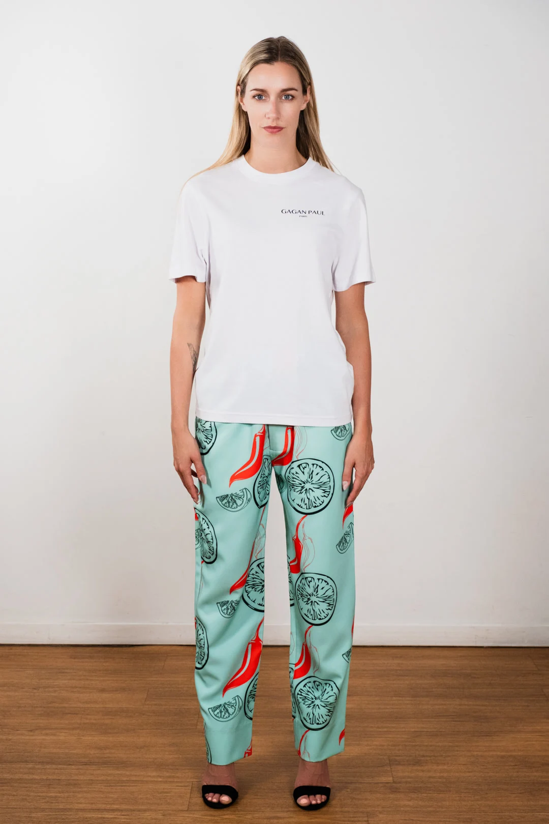 Modèle photographiée en pied portant un tee-shirt blanc et un pantalon vert illustré Gagan Paul