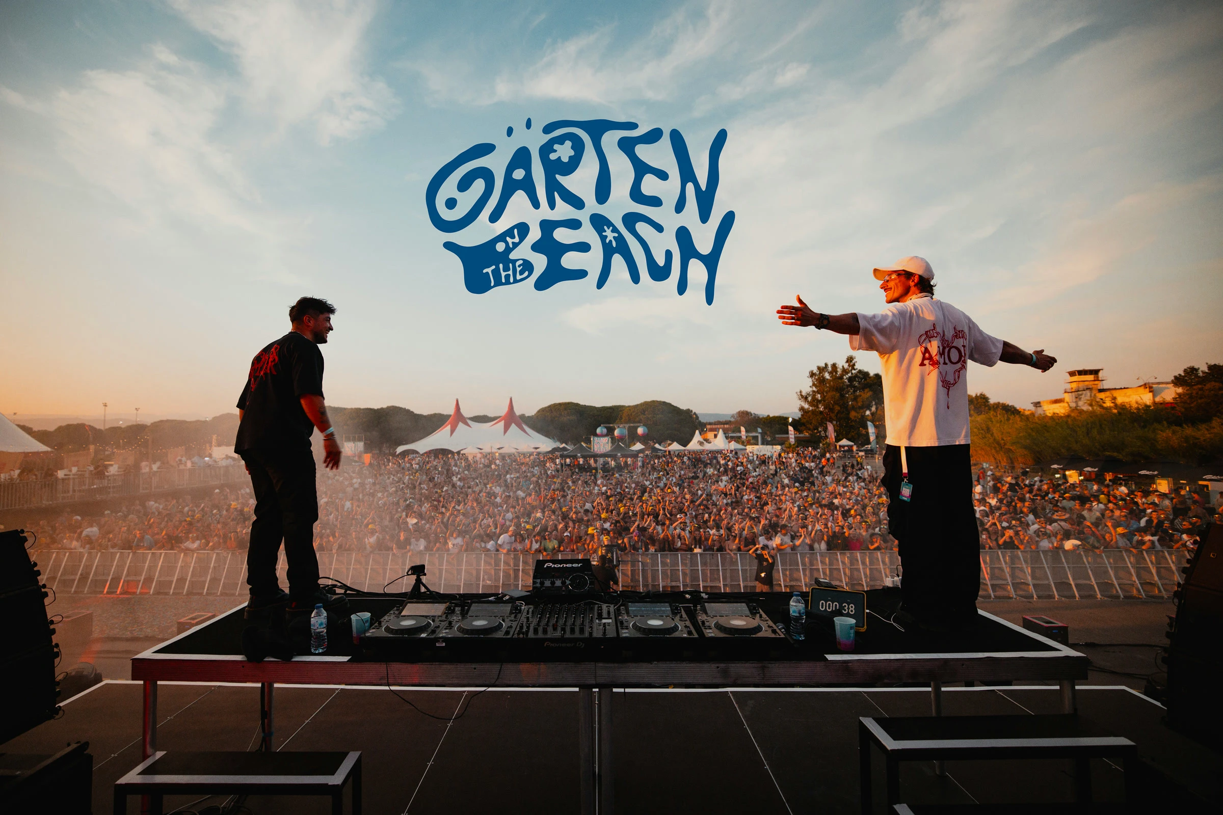 Mise en situation du grand logotype bleu Garten On The Beach sur une photographie de concert, face au public au coucher du soleil