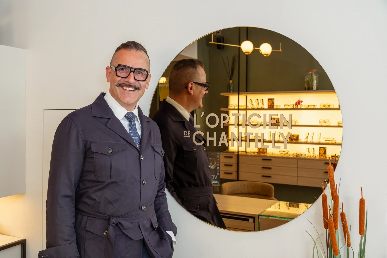 Jérémy Acoca devant le miroir portant le logotype L’Opticien de Chantilly