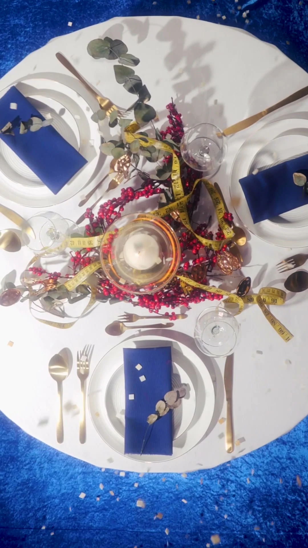 Table ronde dressée pour quatre personnes sur un fond de velours bleu avec des confettis