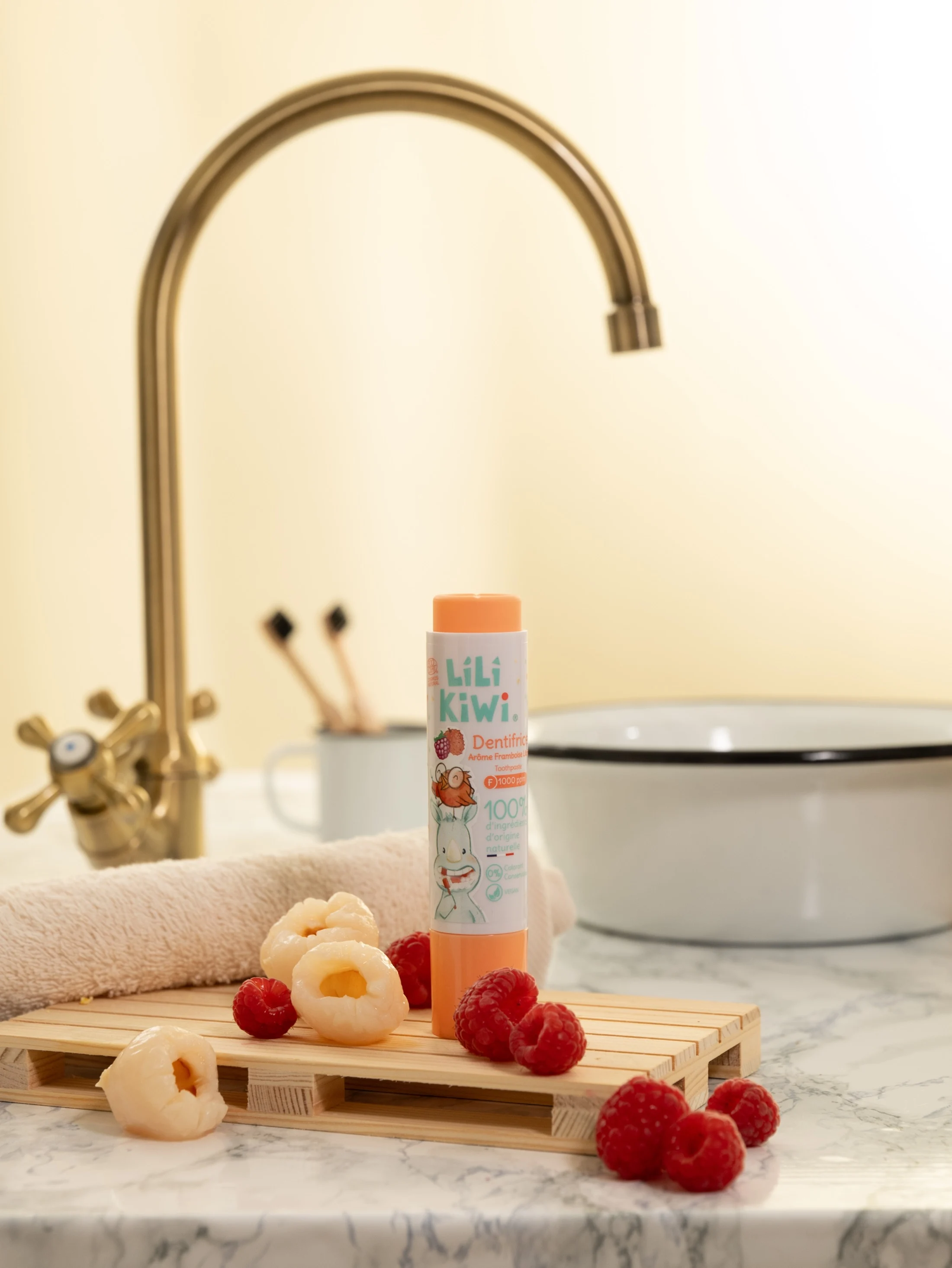 Dentifrice Lili Kiwi orange photographié avec des framboises et des litchis