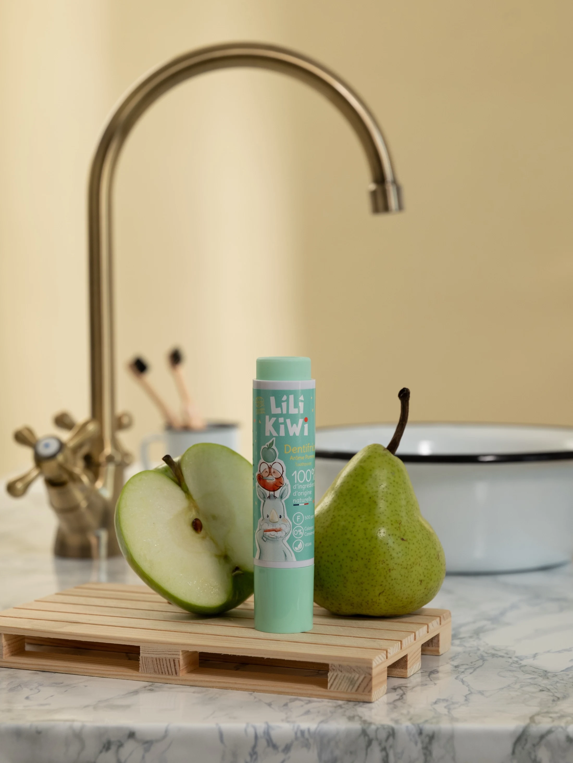 Dentifrice Lili Kiwi vert d’eau photographié avec des poires dans une salle de bain