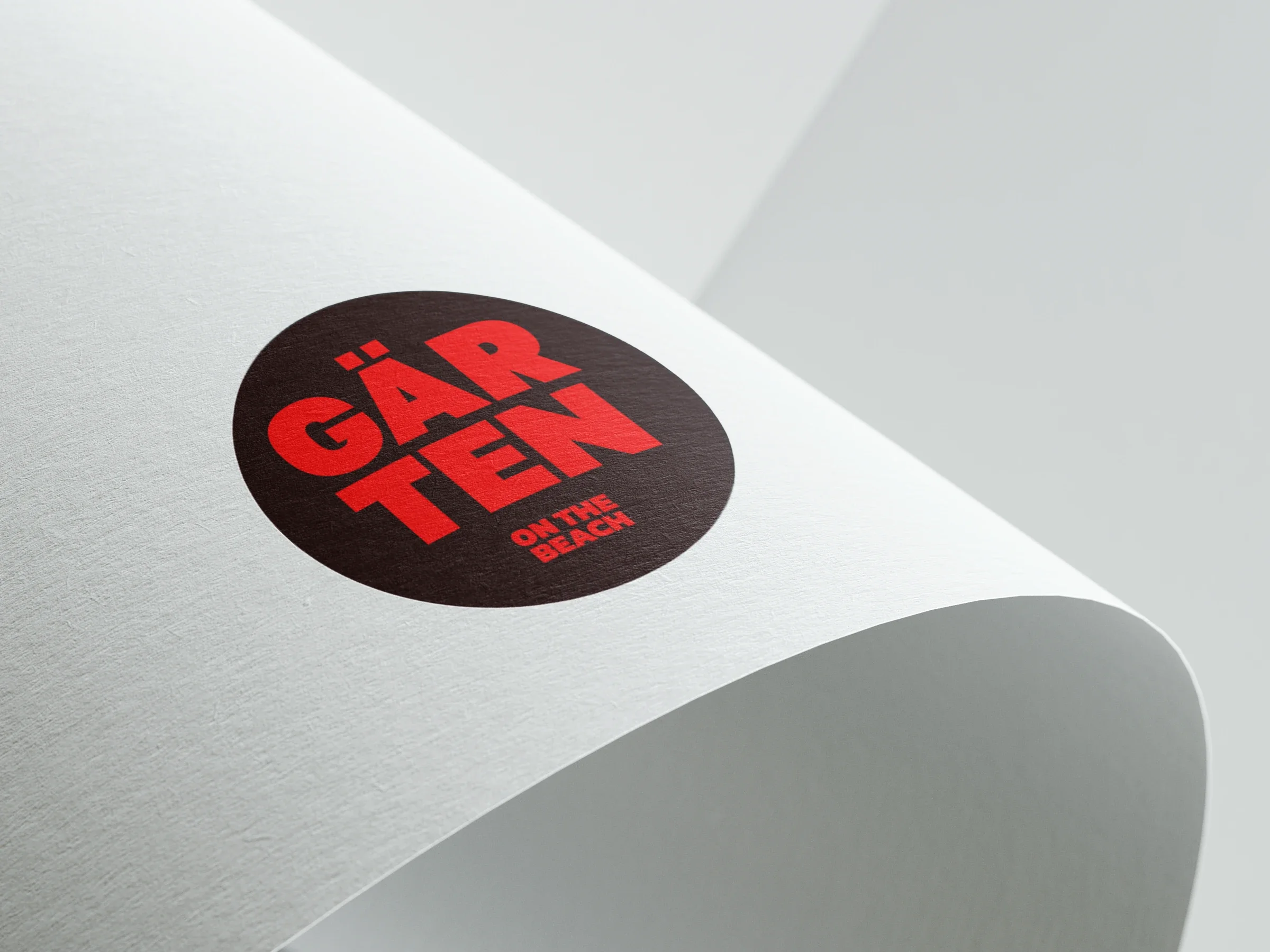 Maquette du logotype compact Garten rouge sur un disque sombre imprimé sur papier, proposition non retenue