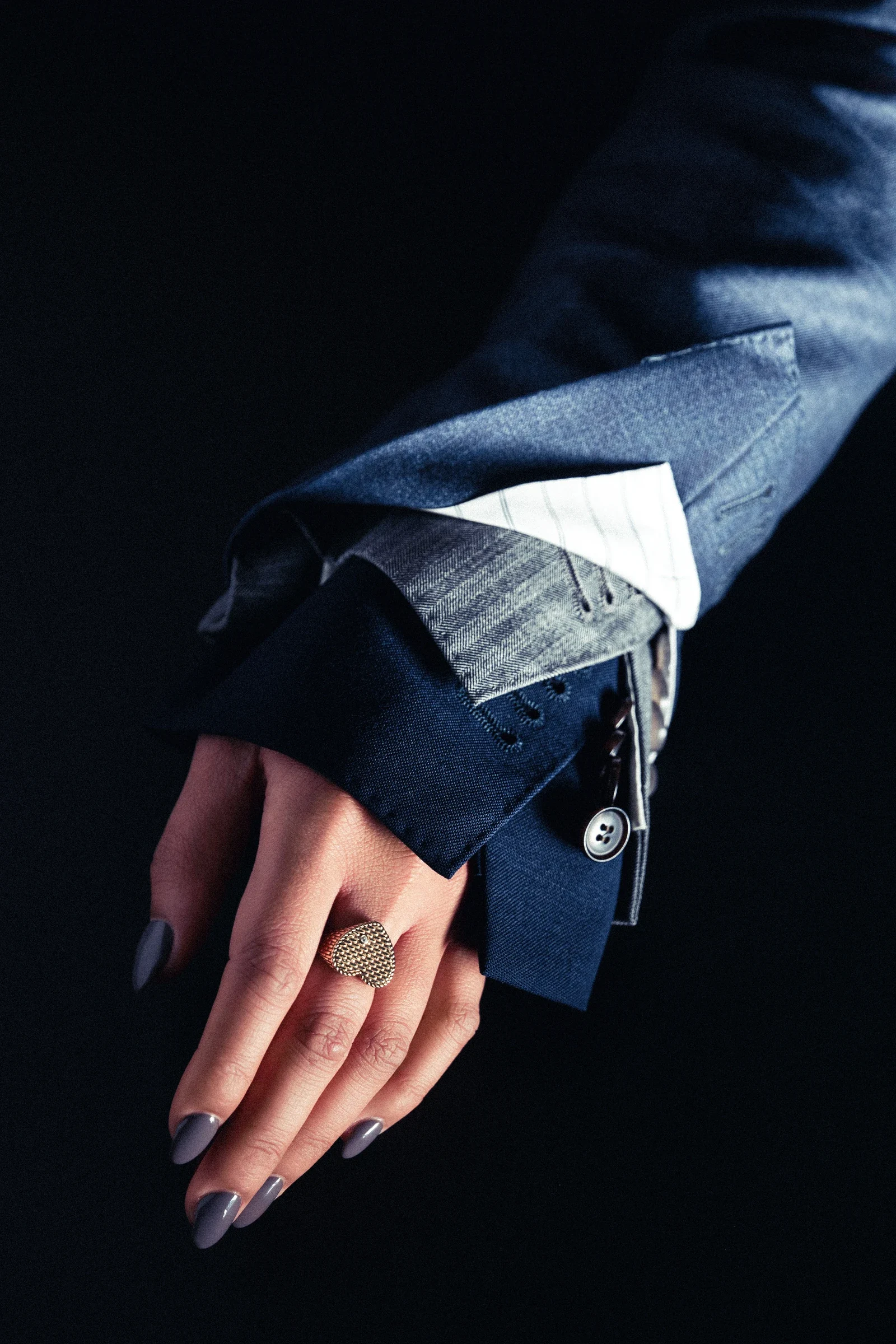 Main et manche en denim dont le poignet est prolongé par des pliages pointus