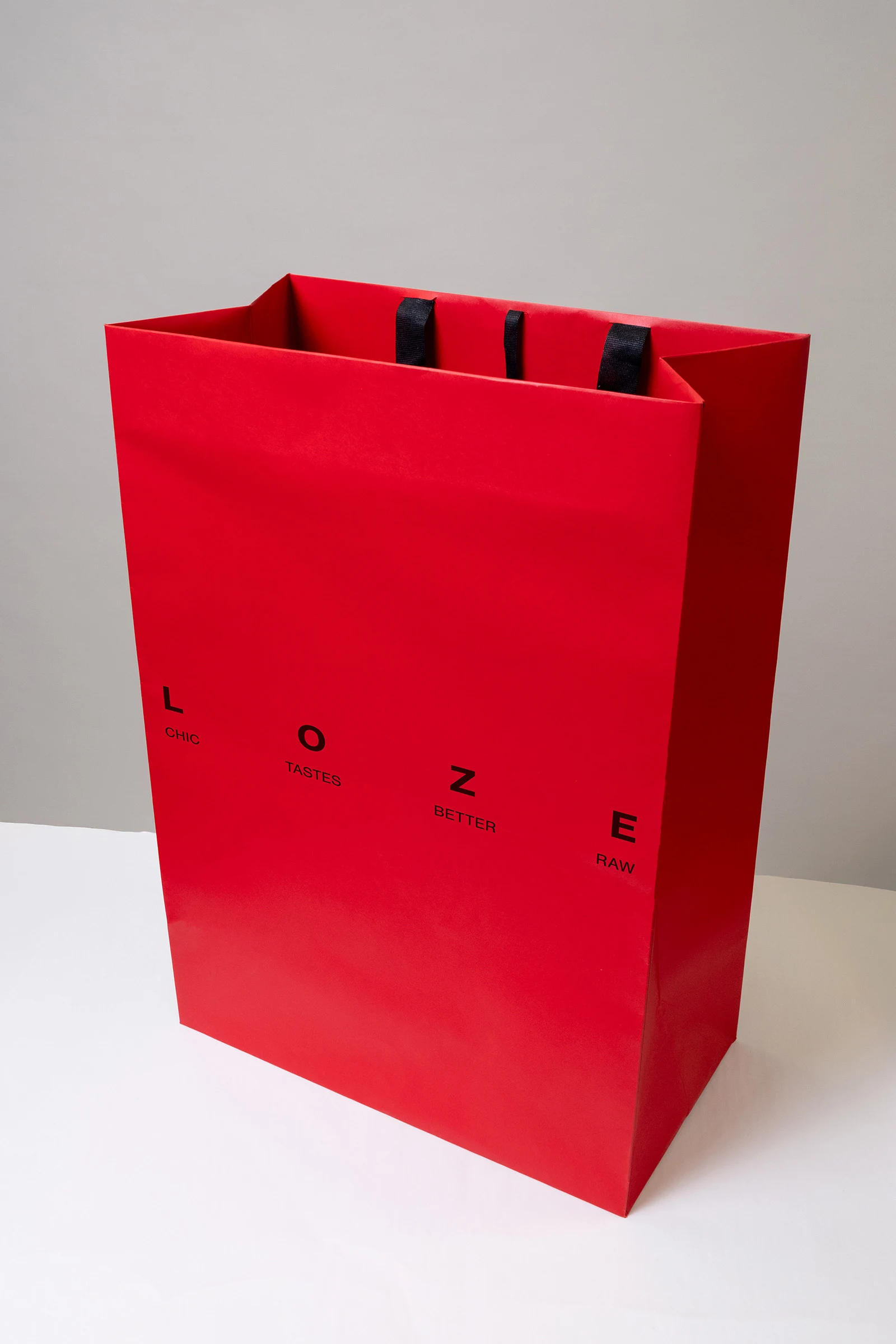 Sac rouge LOZE portant le mot-signe noir et les mots du manifeste