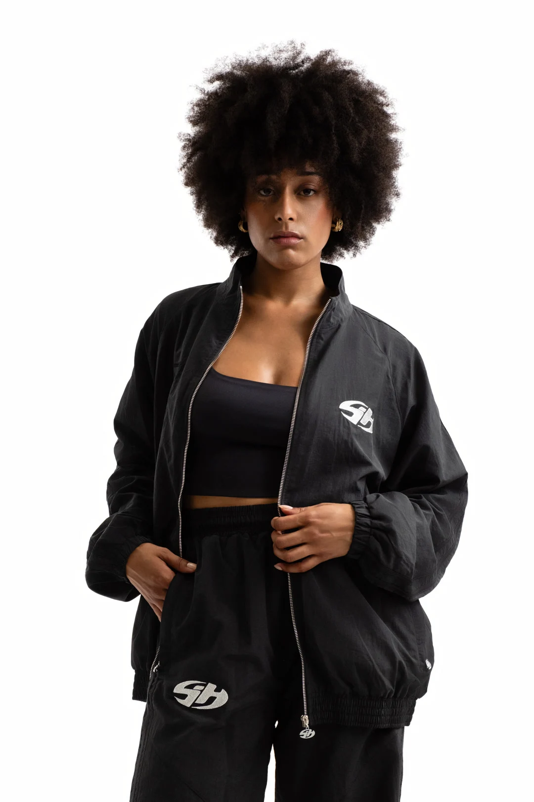 Modèle portant un ensemble noir Sixty House avec veste ouverte et monogramme blanc